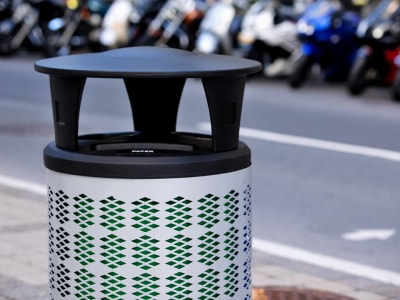 silver metal waste and recycling container with a plastic canopy lid sitting on the sidewalk in a busy city