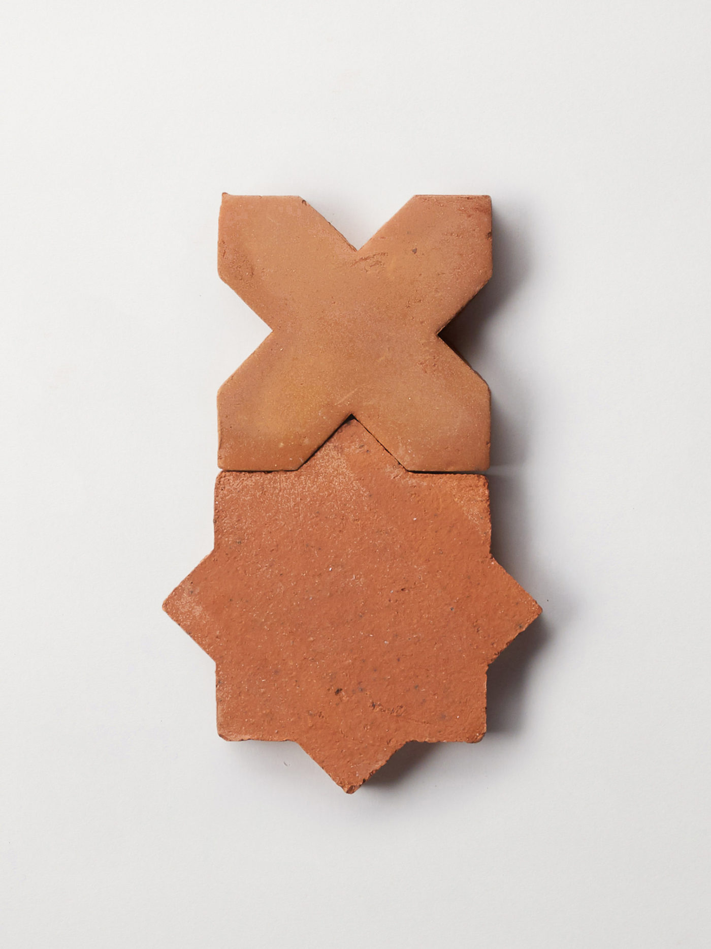 2 pieces of ornamental terracotta tile against a white surface.