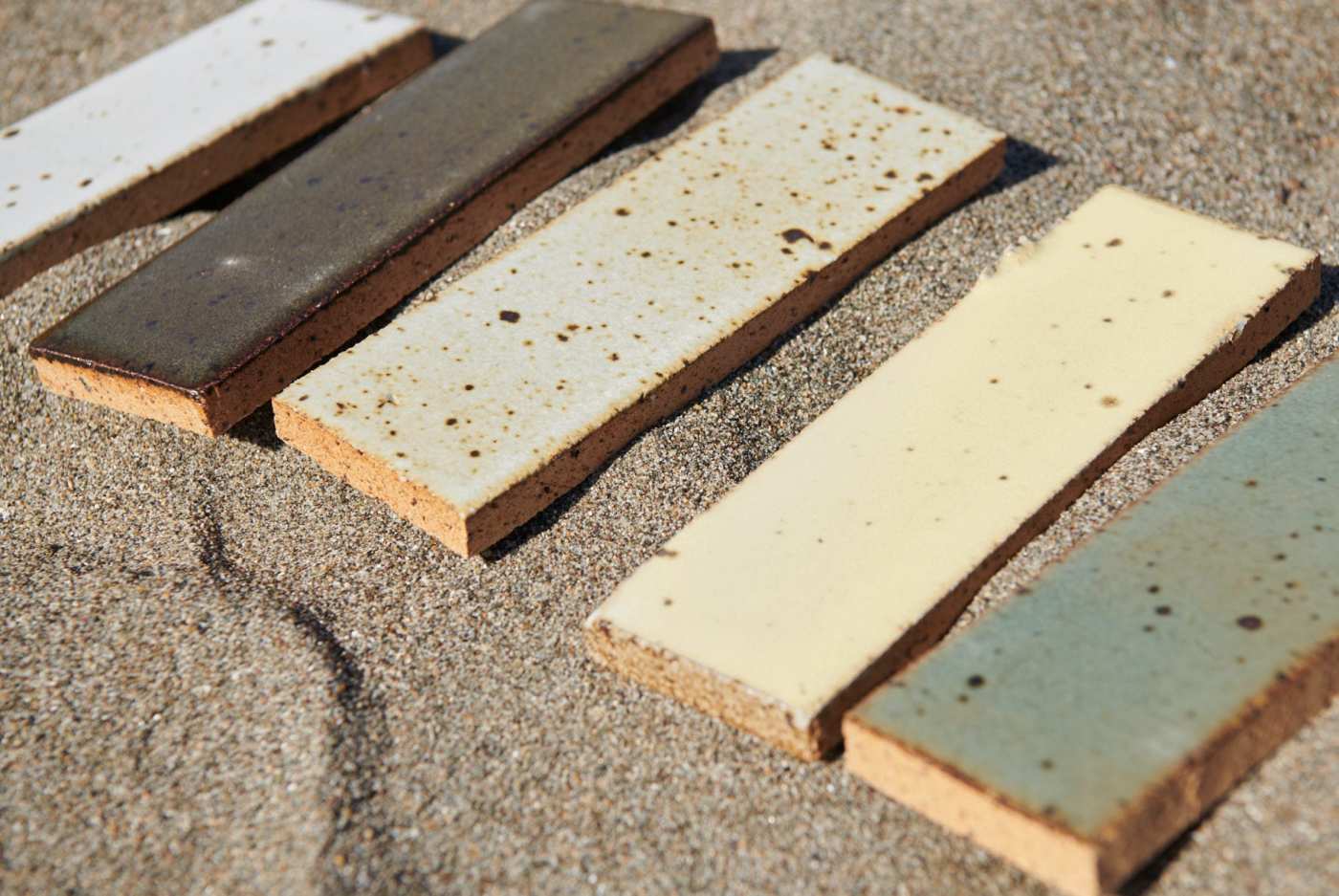 several multicolored ceramic tiles laid out on the sand.