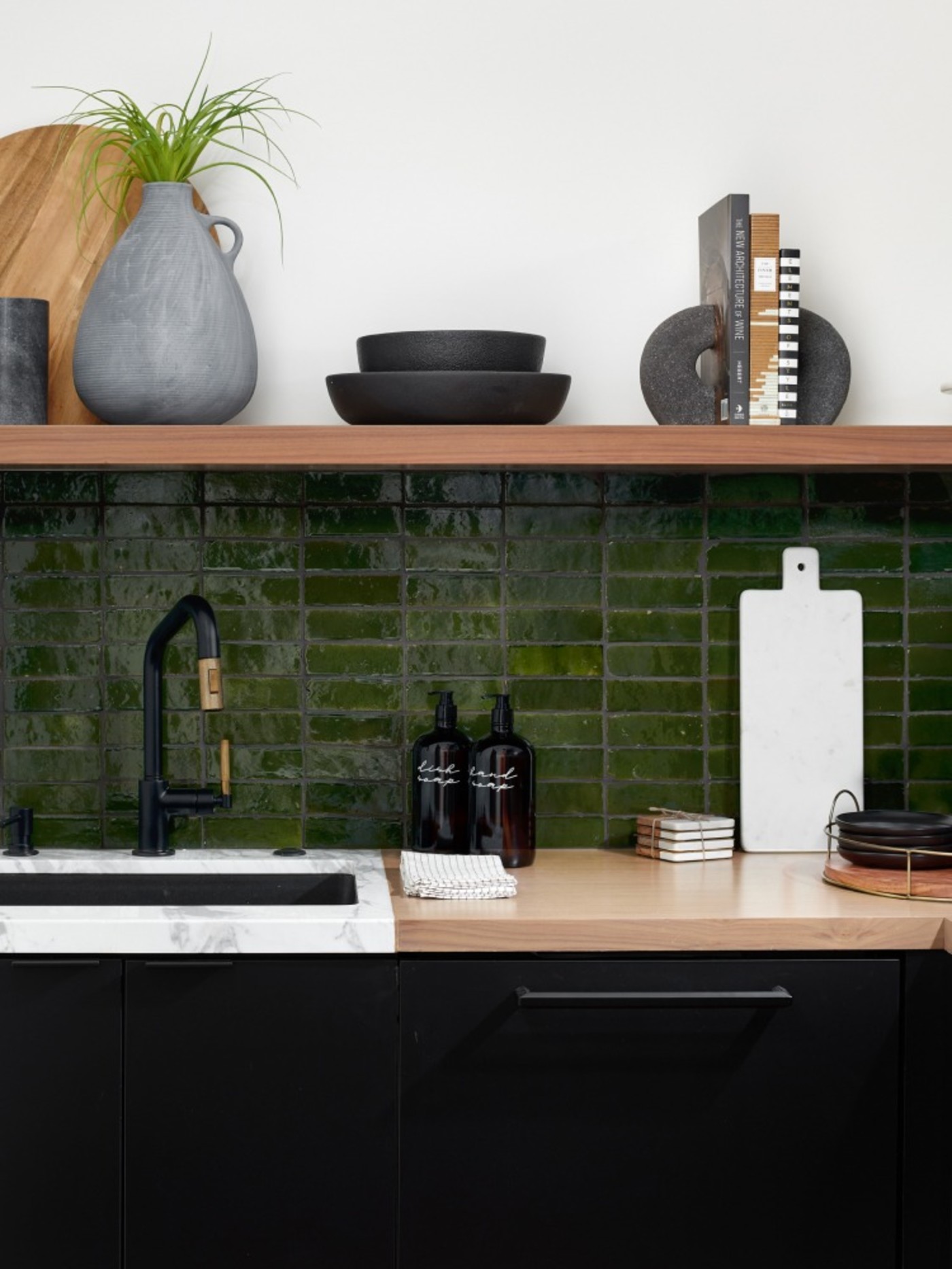 a kitchen with black cabinets and green tile backsplash.