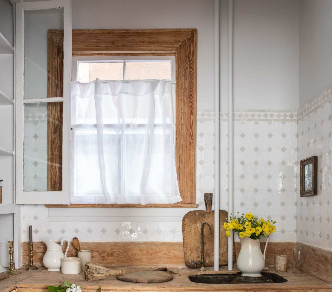 a white kitchen with wooden counter tops and a window.