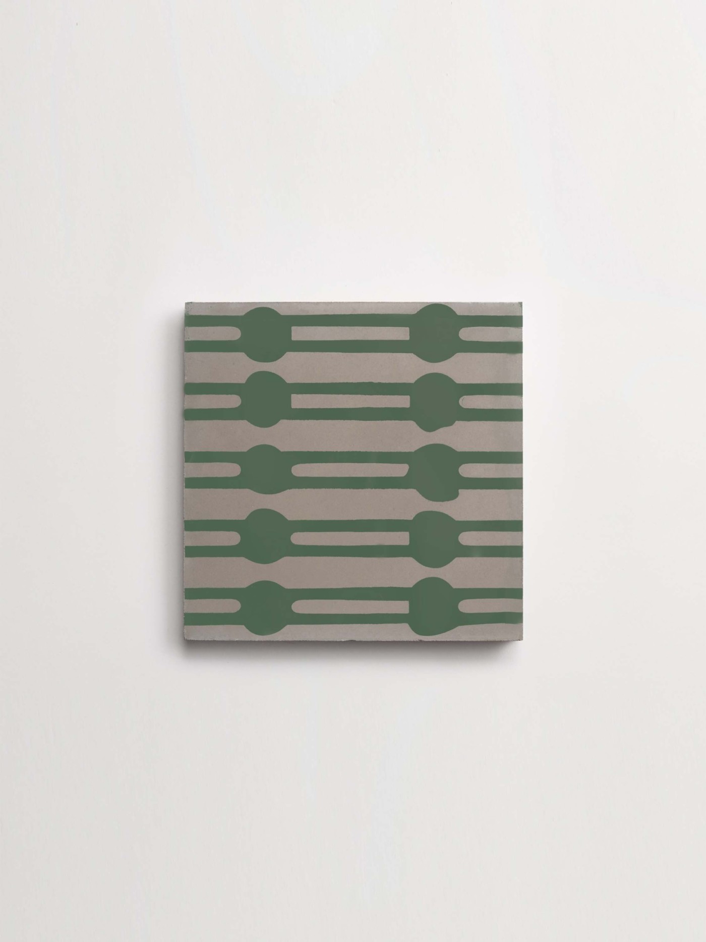 a green and grey patterned tile on a white surface.