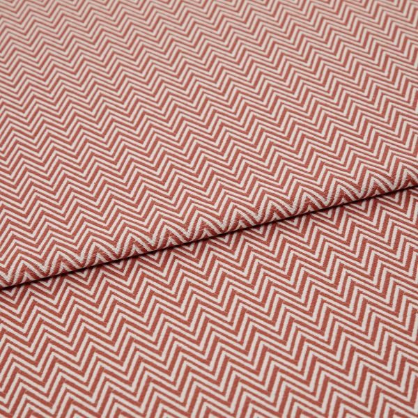 Chevron-patterned textile (red and white) folded across the frame, showing tight zigzag lines; fabric lies flat with a single fold, photographed in even studio lighting on a neutral background.