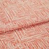 Folded coral-and-cream fabric with textured concentric-square print; a layered fold reveals repeating pattern, shown close-up on a flat surface under soft, even lighting.
