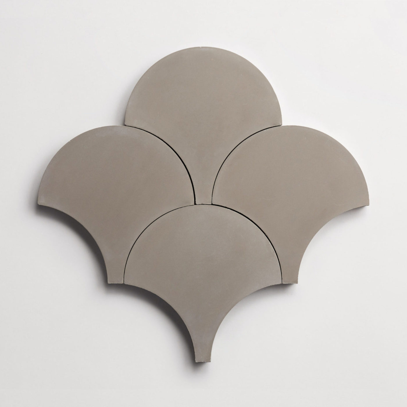 four grey scallop-shaped tiles on a white surface.