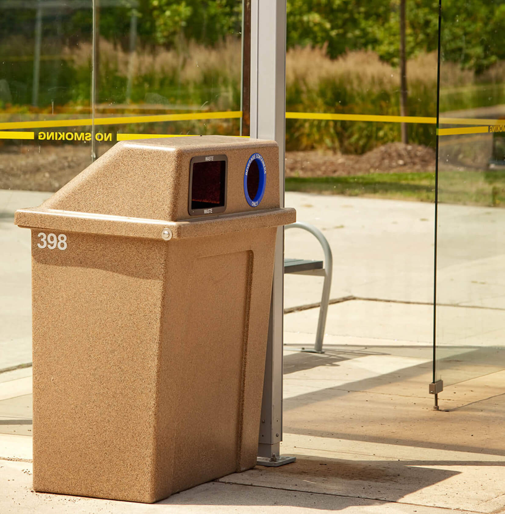 durable LDPE plastic waste and recycling container with hinged lid placed beside a transit shelter on a municipal sidewalk
