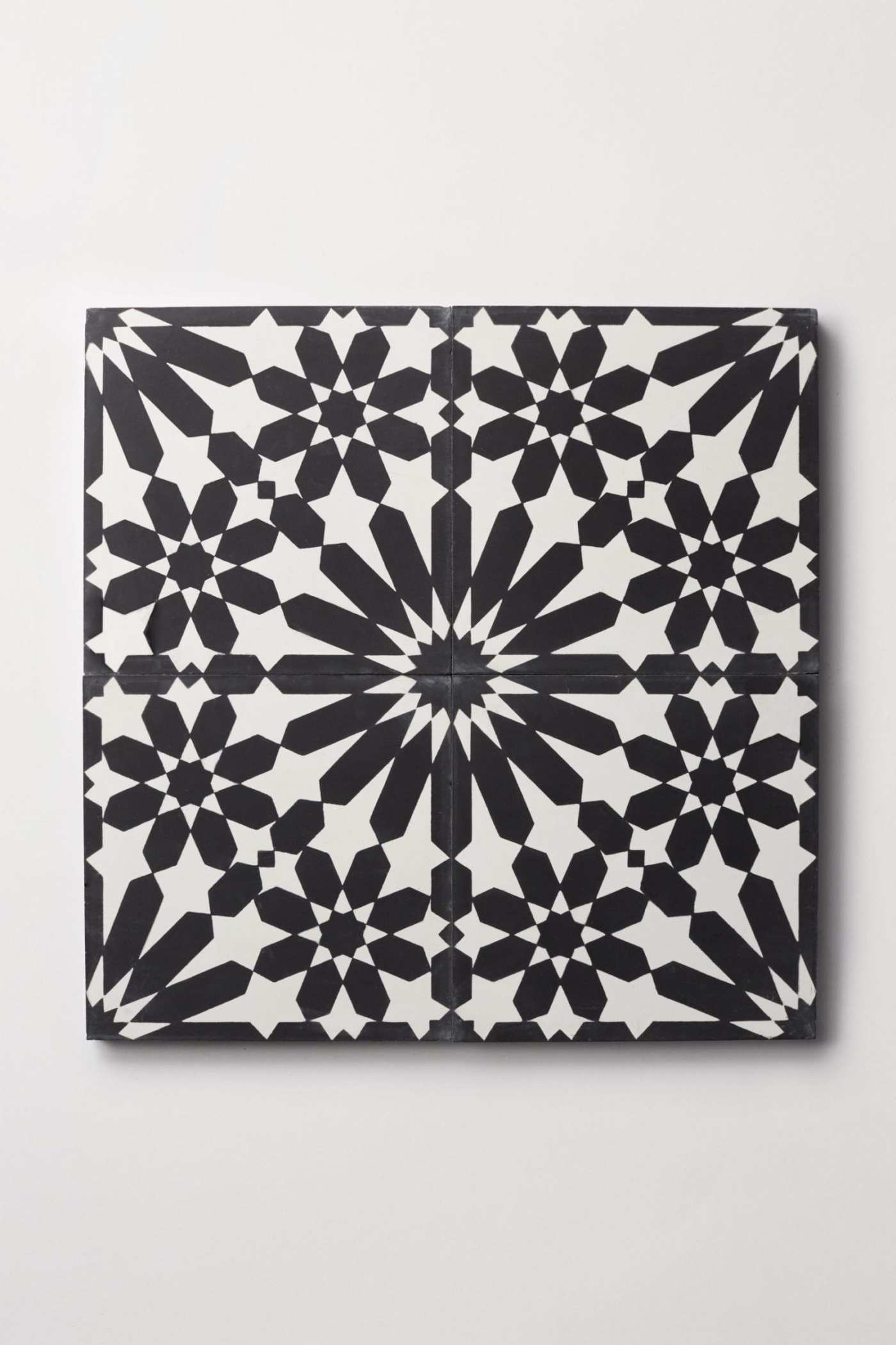 four black and white tiles forming an ornate pattern.