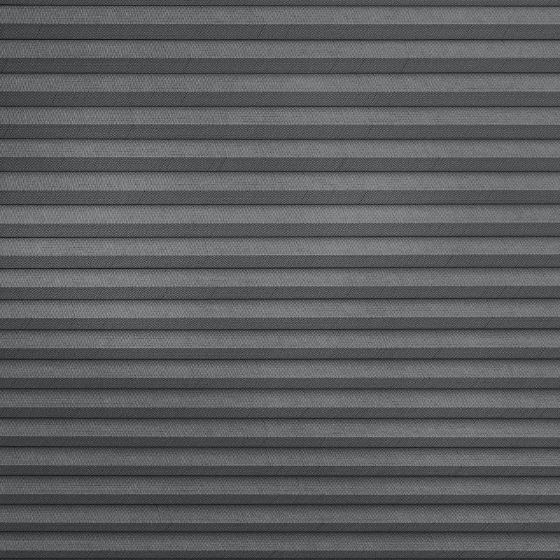 Horizontal fabric pleated blind, fully lowered and closed, featuring narrow gray ridged folds; blocking light and creating uniform texture across a neutral, softly lit interior window.