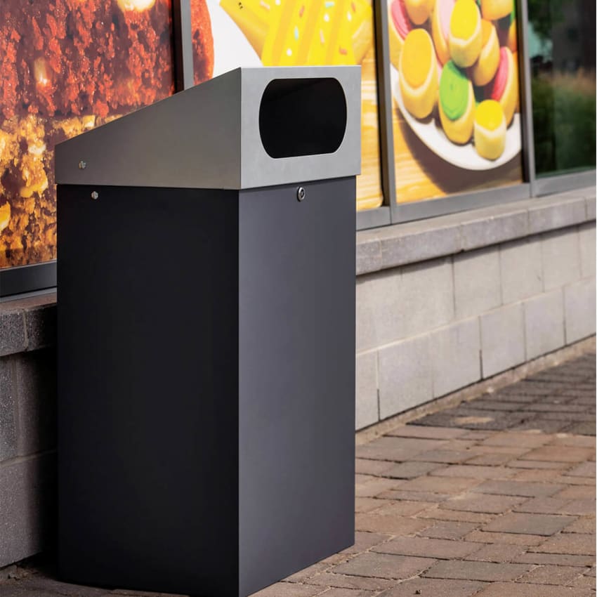 durable powder coated steel outdoor trash bin with locking lid and large waste opening outside a shopping plaza