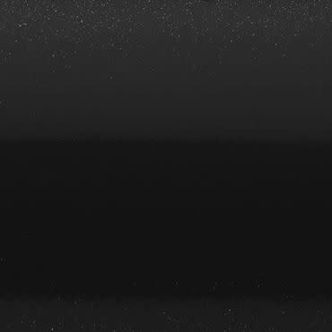 Star-speckled black sky — tiny points scattered unevenly — with a faint horizontal mid-band and indistinct dark horizon suggesting a dim, minimalist nocturnal scene.