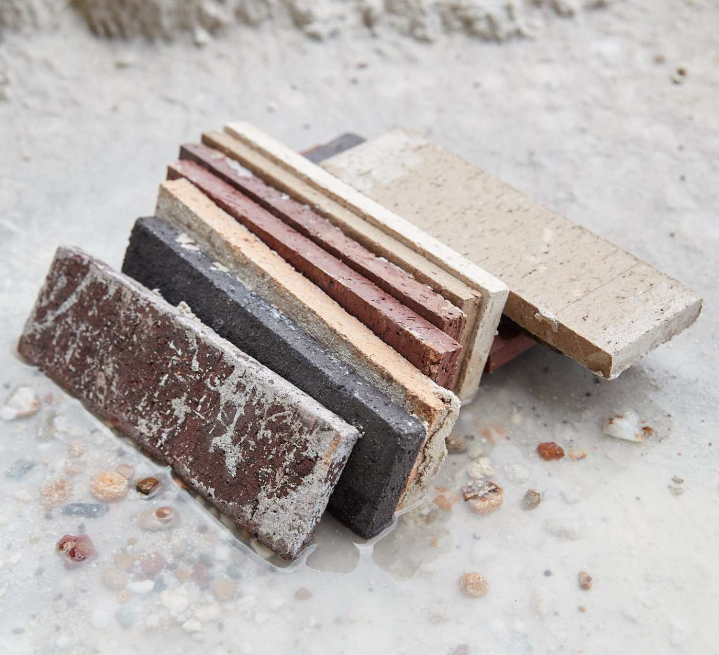 a pile of various colored bricks laying in the sand.