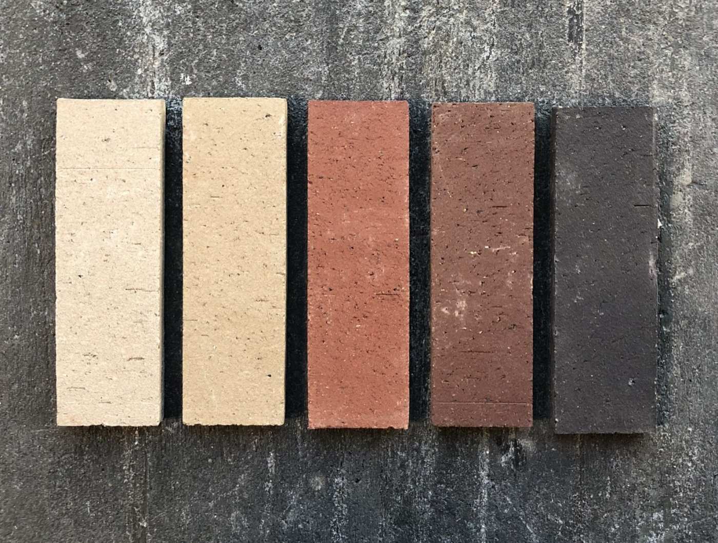 five different colored bricks on a concrete surface.