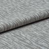 Folded grey woven fabric with raised, wavy ribbed texture (object) layered across itself (action) in a close-up, neutral-lit studio view emphasizing tactile detail (context).