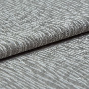 Folded grey woven fabric with raised, wavy ribbed texture (object) layered across itself (action) in a close-up, neutral-lit studio view emphasizing tactile detail (context).