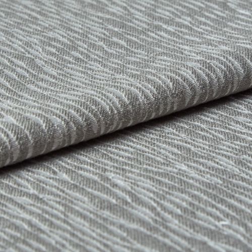 Folded grey woven fabric with raised, wavy ribbed texture (object) layered across itself (action) in a close-up, neutral-lit studio view emphasizing tactile detail (context).