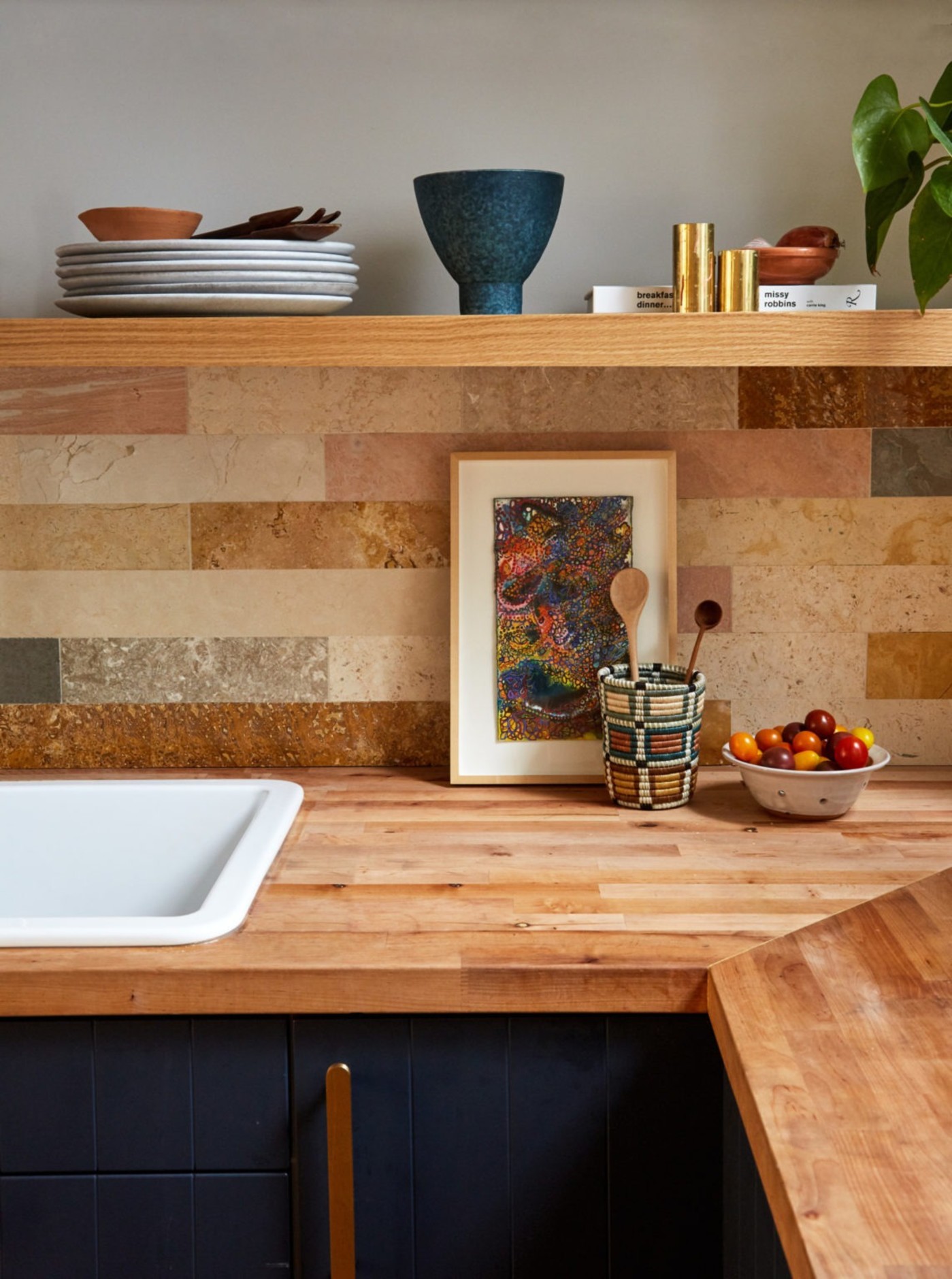 a kitchen with a wooden counter top, a sink and a tile backsplash.