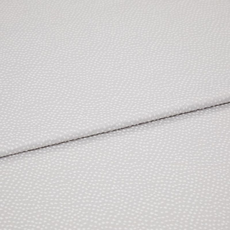 Light-gray fabric with small white dotted texture, folded diagonally with an overlapping edge; close-up view on a plain surface under soft, even lighting.