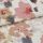 Folded floral-patterned fabric panel — watercolor-style pink, mauve and gray blooms on a pale background — overlapping fold across center, close-up view under soft, diffuse lighting.
