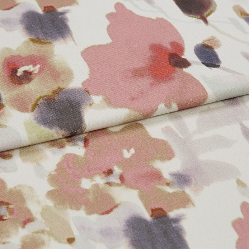 Folded floral-patterned fabric panel â€” watercolor-style pink, mauve and gray blooms on a pale background â€” overlapping fold across center, close-up view under soft, diffuse lighting.