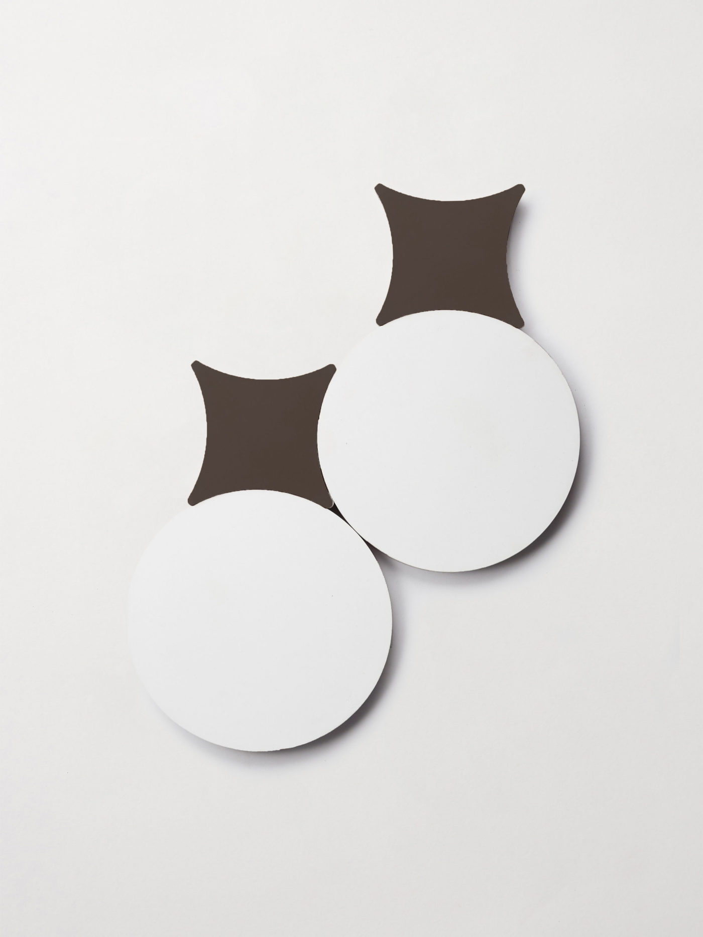 a pair of white circular tiles and black cross shaped tiles on a white surface.