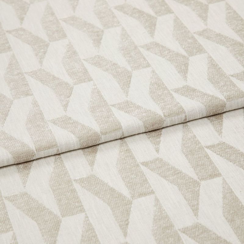 Beige-and-ivory geometric woven fabric with repeating angular, three-dimensional pattern; folded over itself, showing texture and slight sheen; studio-lit close-up on a neutral background, suited for upholstery or curtains.