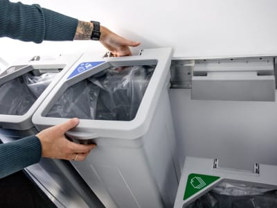 grey recycling station being hung on a wall using a strong wall bracket system