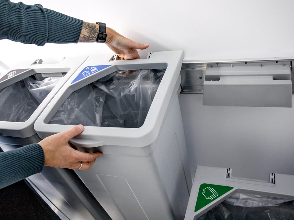 grey recycling station being hung on a wall using a strong wall bracket system