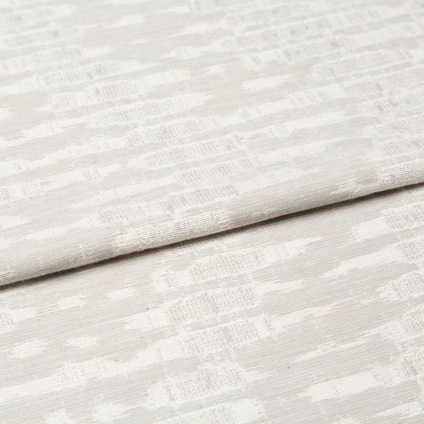 Off-white woven curtain fabric folded horizontally, showing a subtle geometric jacquard pattern; soft, diffused light highlights the texture in a neutral, close-up interior view.
