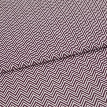 Folded fabric featuring tight purple-and-white chevron stripes, folded to form a shallow diagonal ridge; close-up view of a flat textile sample with even, neutral lighting.