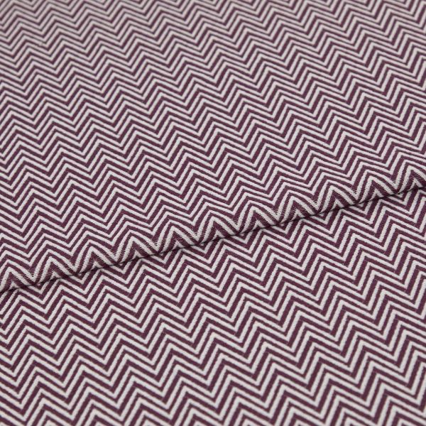 Folded fabric featuring tight purple-and-white chevron stripes, folded to form a shallow diagonal ridge; close-up view of a flat textile sample with even, neutral lighting.