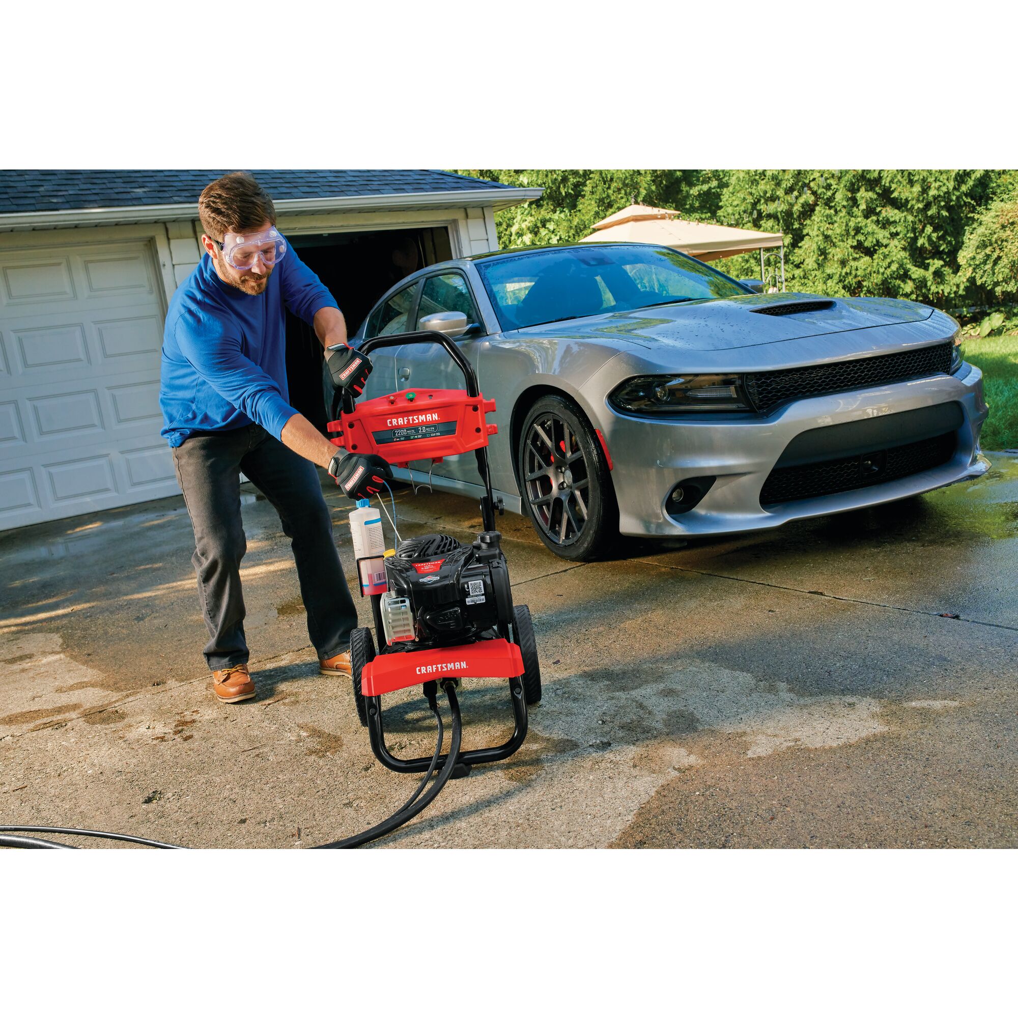 Person gearing up to use 2200 MAX Pounds per Square Inch or 2 MAX Gallons Per Minute Pressure Washer to wash car outdoors.