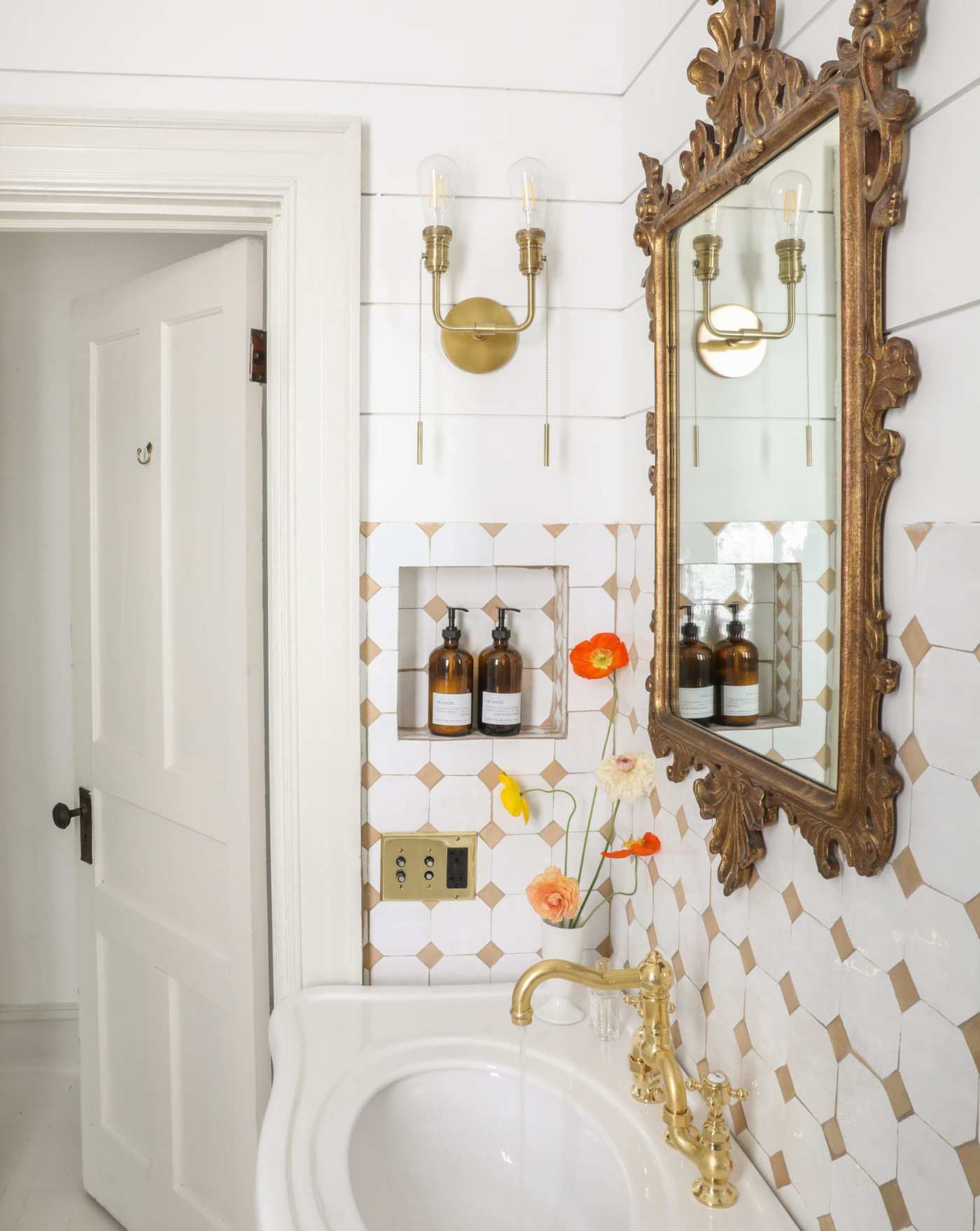 a white bathroom with a gold mirror and tiled walls.