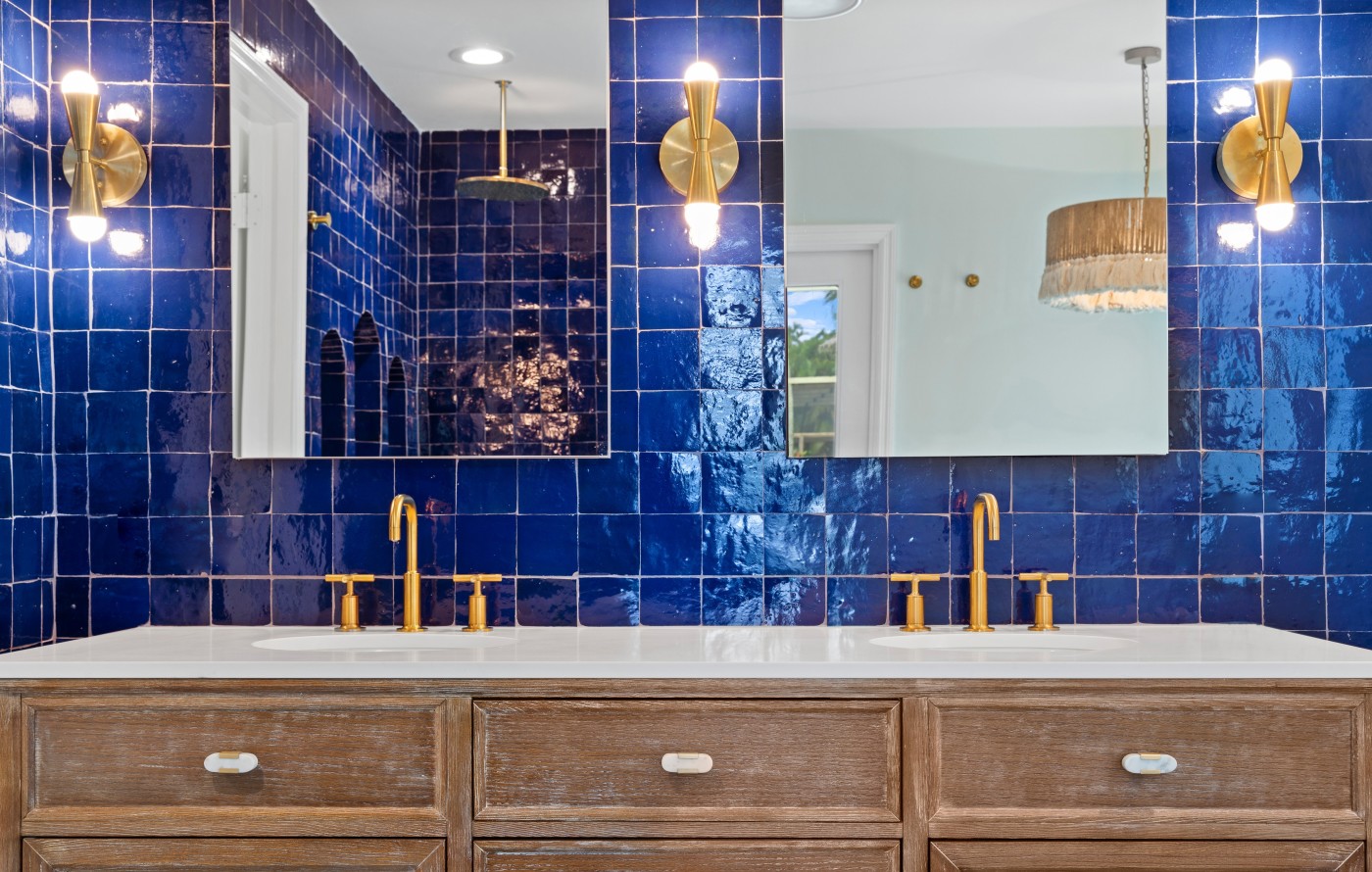 a bathroom with blue tile and gold fixtures.