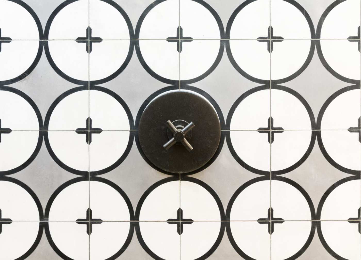 a shower with black and white tiles forming cross patterns.