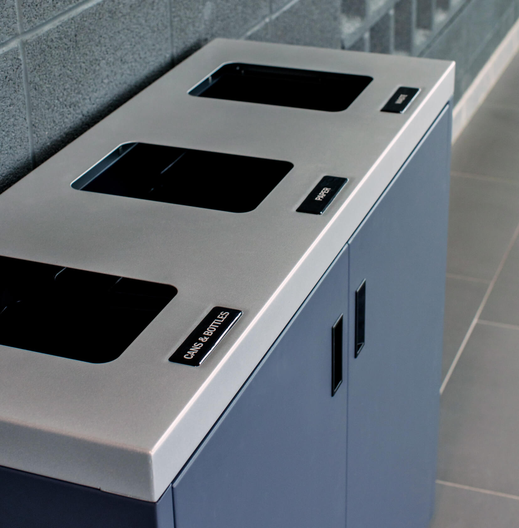 closeup of a metal recycling and waste bin with a silver lid and grey body in a college campus
