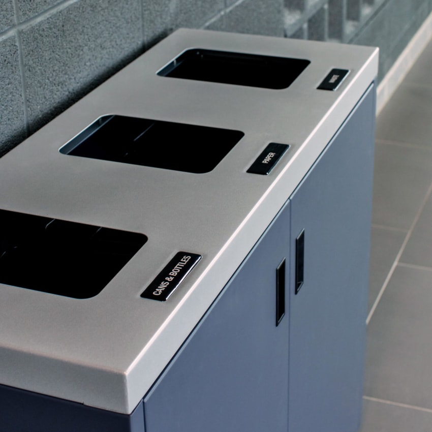 closeup of a metal recycling and waste bin with a silver lid and grey body in a college campus