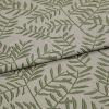 Beige woven fabric panel printed with green fern-like branches (textured weave) — lying with two overlapping folds — close-up on a neutral surface under soft, even lighting.