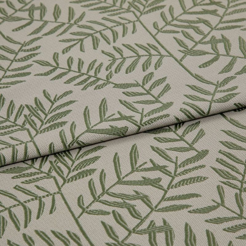 Beige woven fabric panel printed with green fern-like branches (textured weave) â€” lying with two overlapping folds â€” close-up on a neutral surface under soft, even lighting.