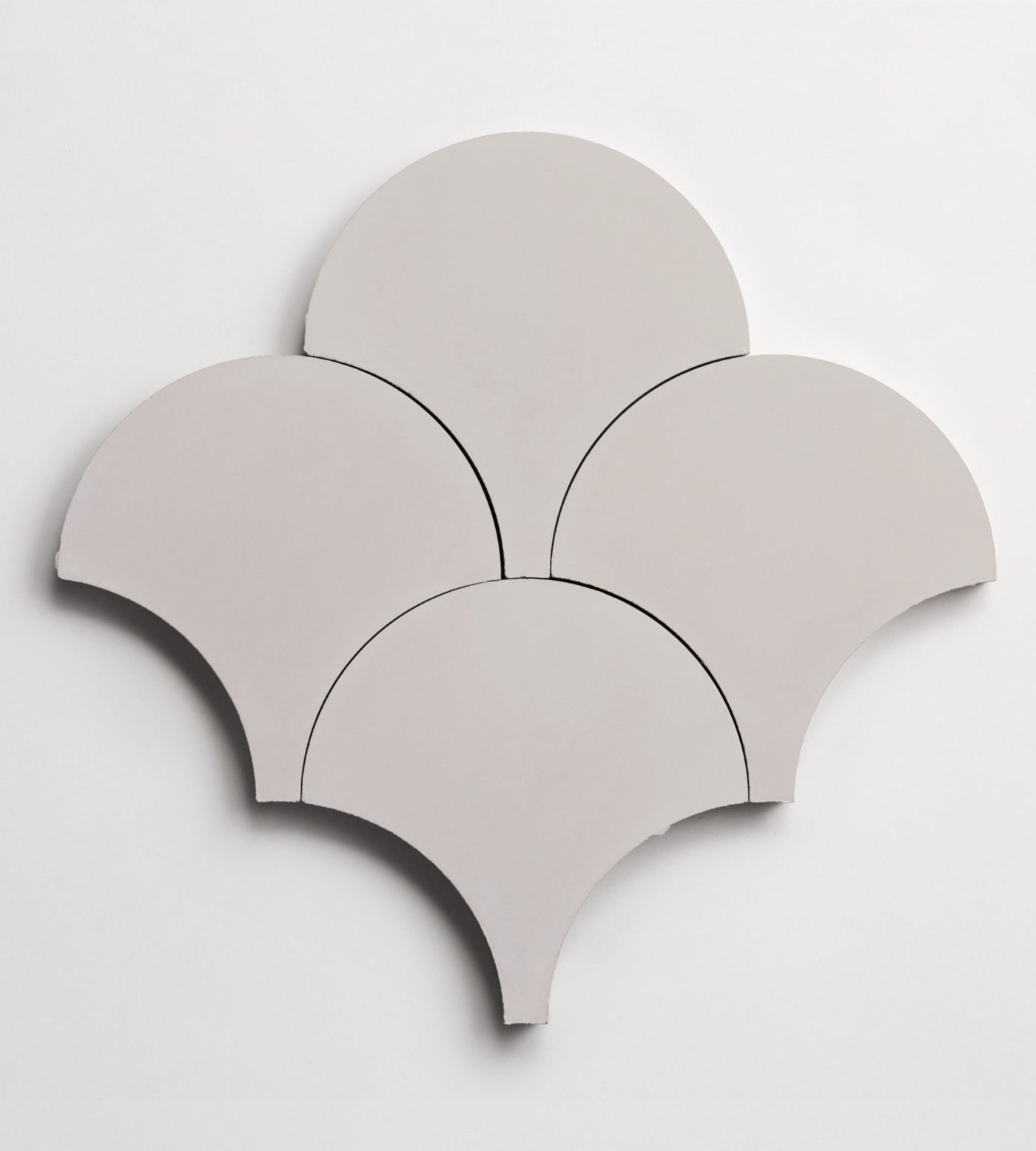 four grey scallop-shaped tiles on a white surface.