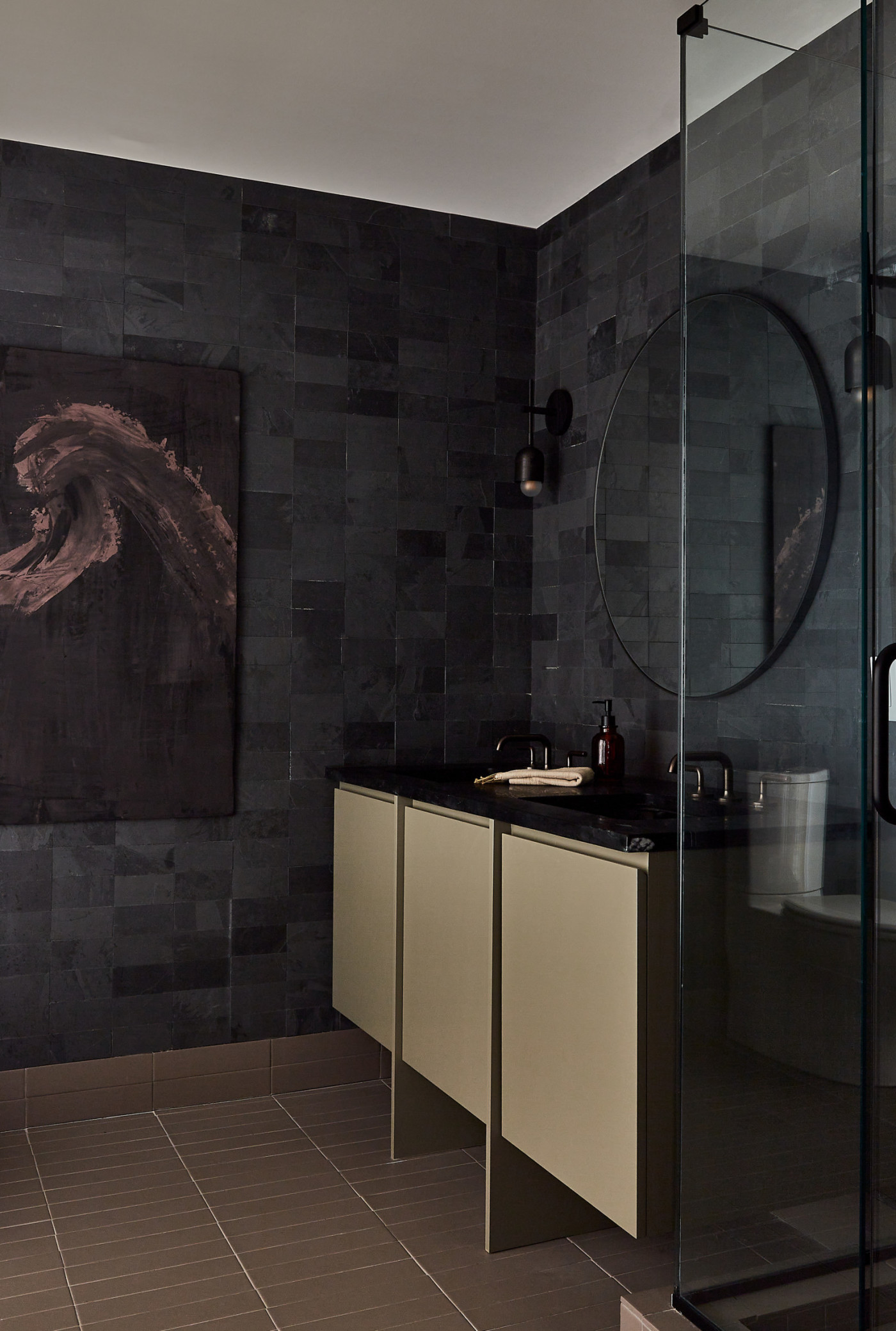 a black tiled bathroom with a glass shower.