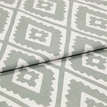 Folded woven fabric featuring repeating jagged-diamond, Aztec-like motif in sage green and off-white â€” layered across itself, lying flat in a soft, evenly lit close-up highlighting weave texture.