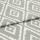 Folded woven fabric featuring repeating jagged-diamond, Aztec-like motif in sage green and off-white — layered across itself, lying flat in a soft, evenly lit close-up highlighting weave texture.