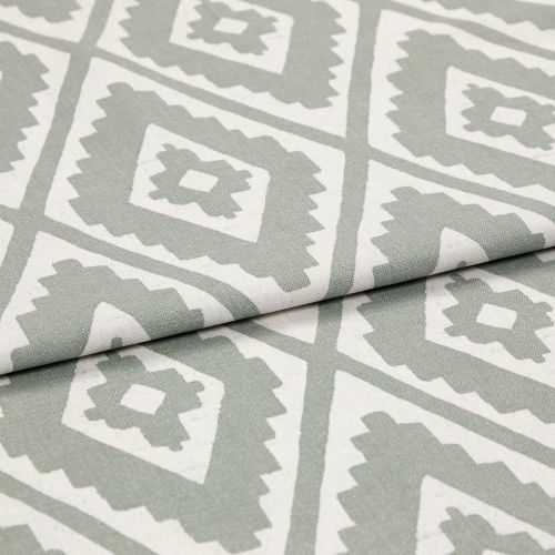 Folded woven fabric featuring repeating jagged-diamond, Aztec-like motif in sage green and off-white â€” layered across itself, lying flat in a soft, evenly lit close-up highlighting weave texture.