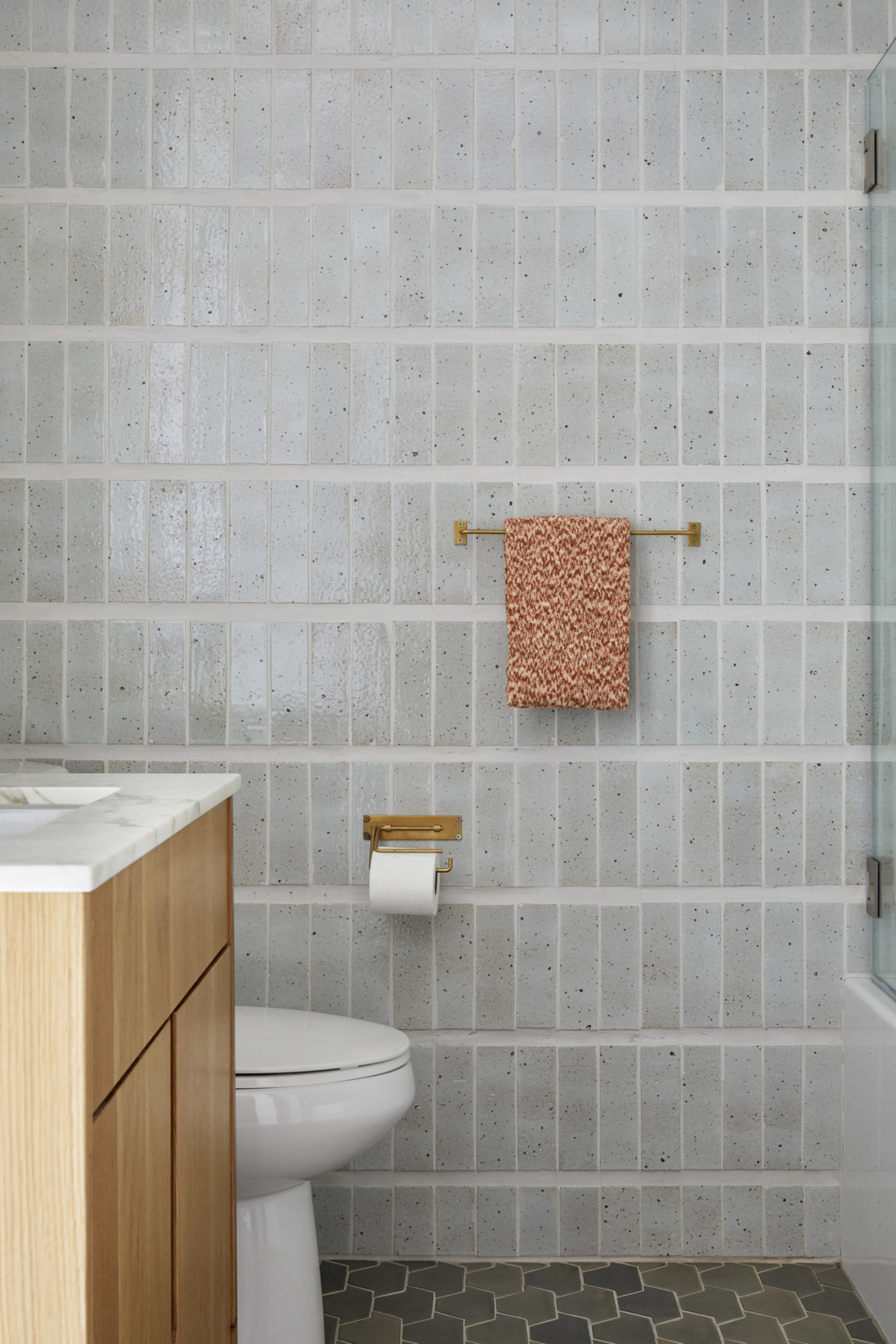 a bathroom with a grey tiled wall, a toilet, and a sink.