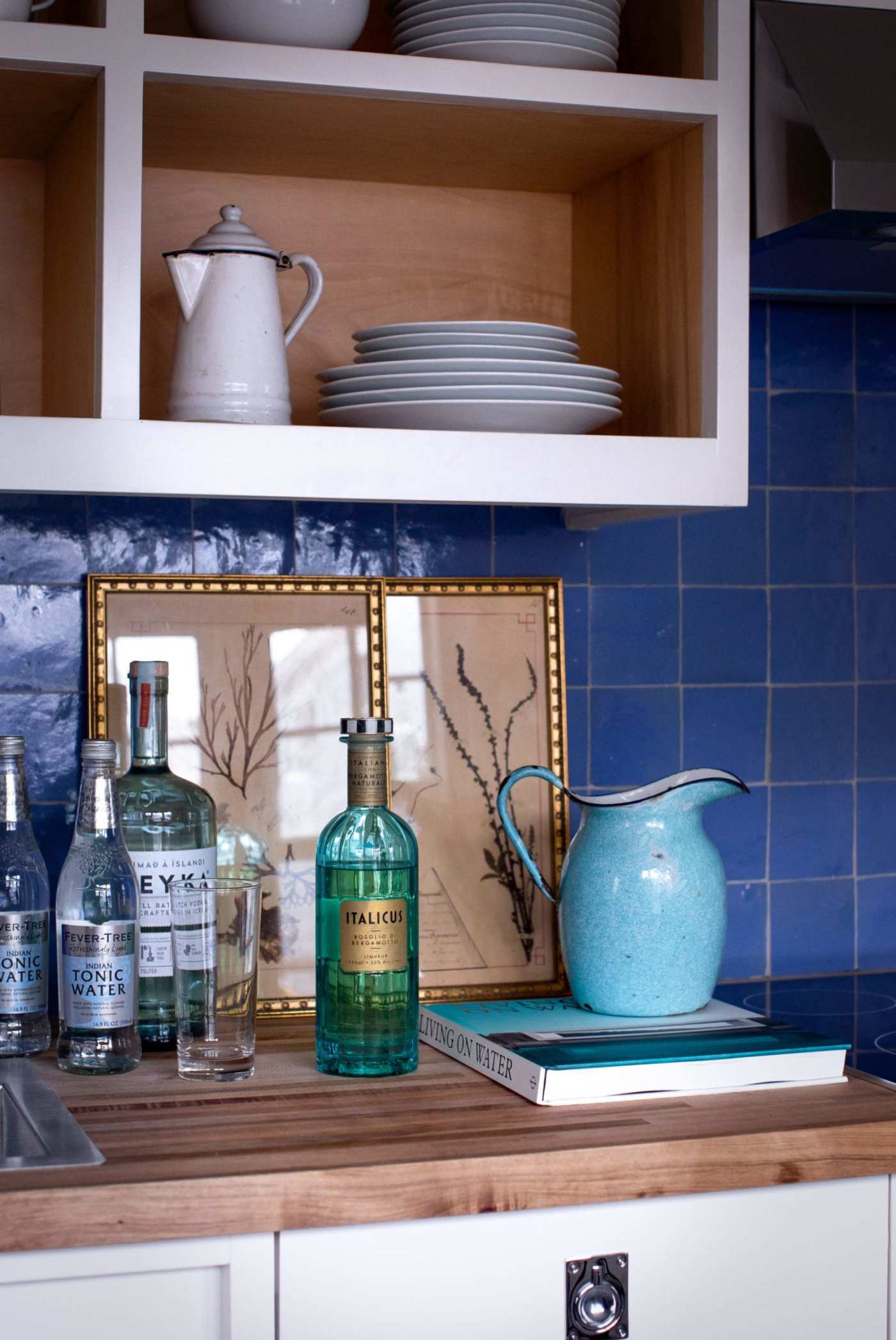 a blue tile backsplash behind a kitchen counter with kitchen items on it.