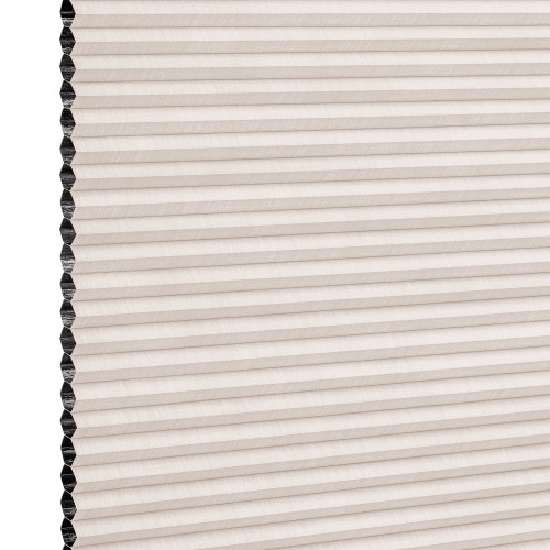 Beige pleated honeycomb cellular blind, fully lowered with visible black cells along the left edge; filtering light in a close-up studio view of the shade surface.