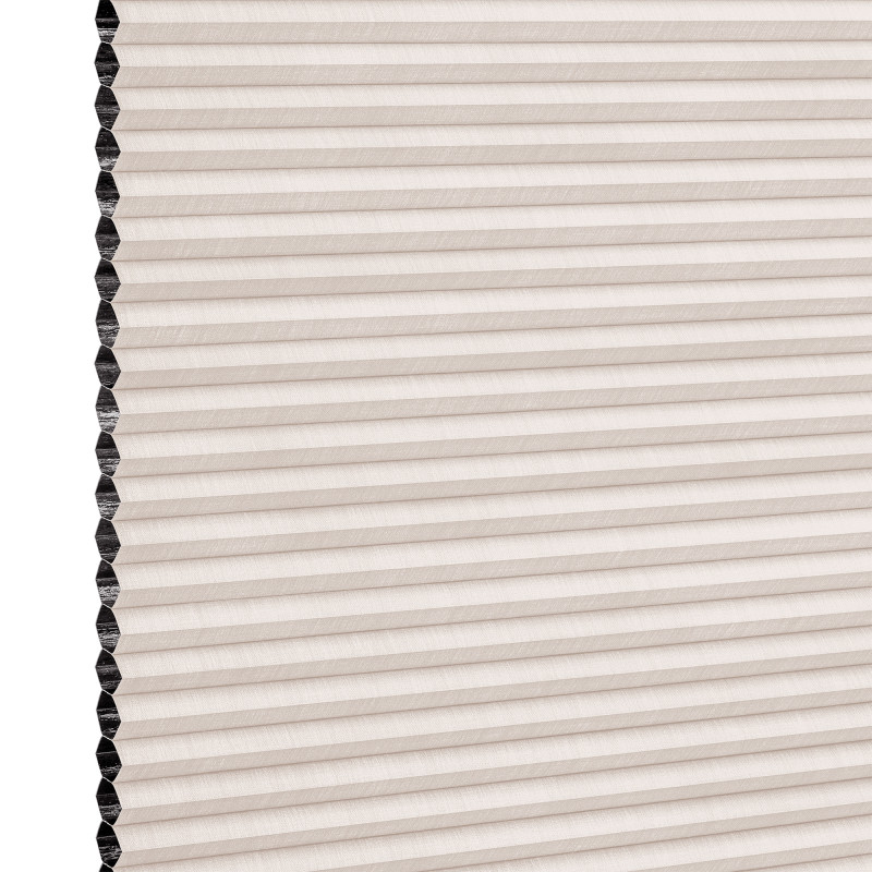 Beige pleated honeycomb cellular blind, fully lowered with visible black cells along the left edge; filtering light in a close-up studio view of the shade surface.