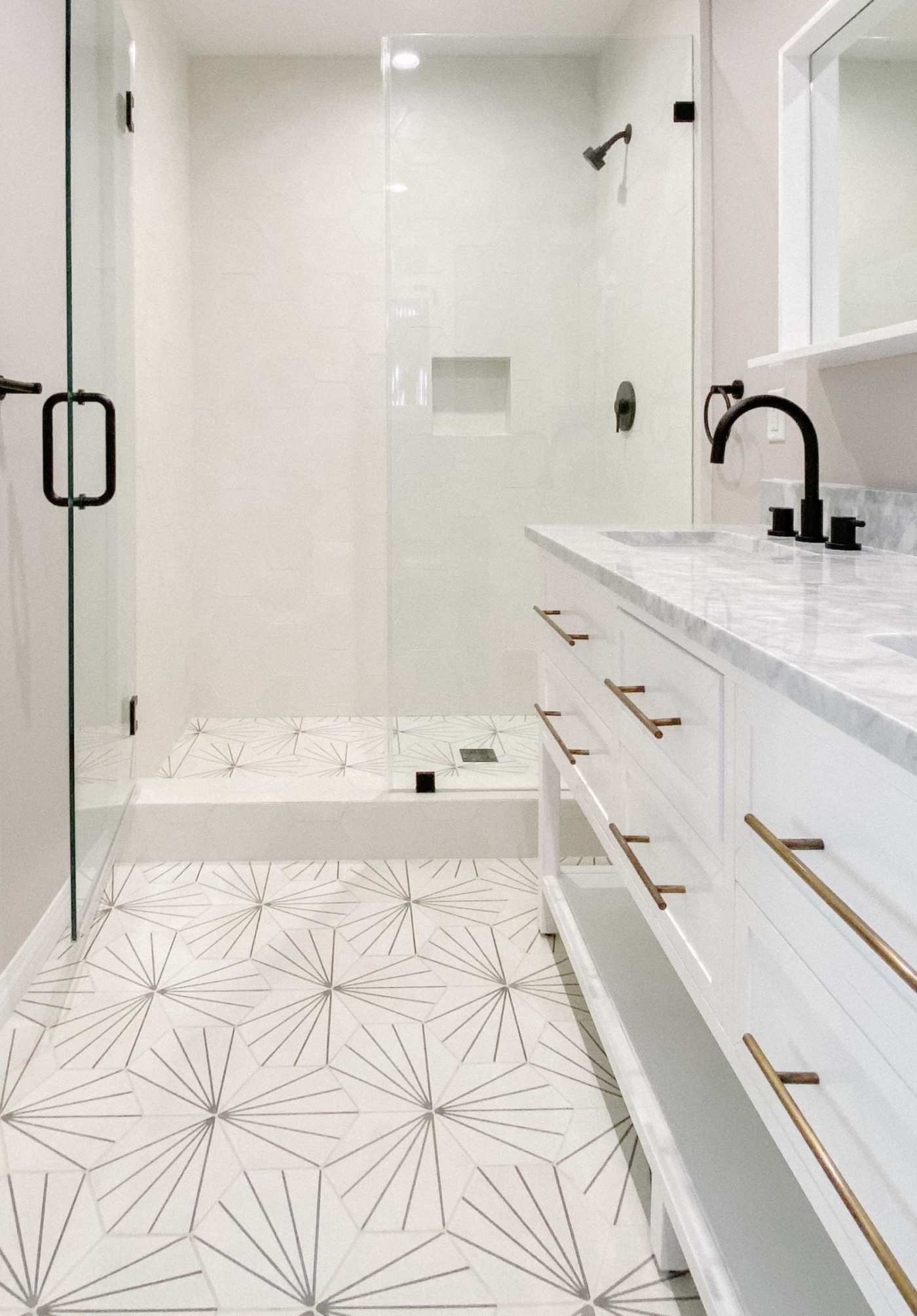 a white and gold bathroom with a glass shower.