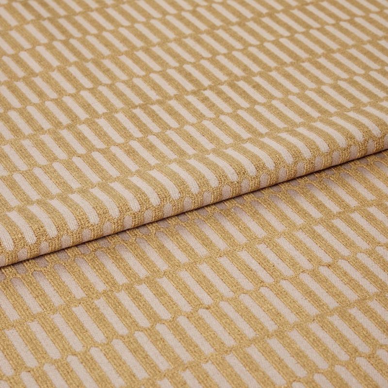 Woven upholstery fabric with a raised golden rectangular grid, folded over itself; pattern repeats diagonally across the surface, shown in a close-up, studio-lit view on a neutral background.