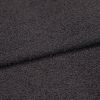 Dark charcoal looped fabric, forming a shallow horizontal fold, close-up studio view emphasizing coarse, pebble-like texture under even, neutral lighting.